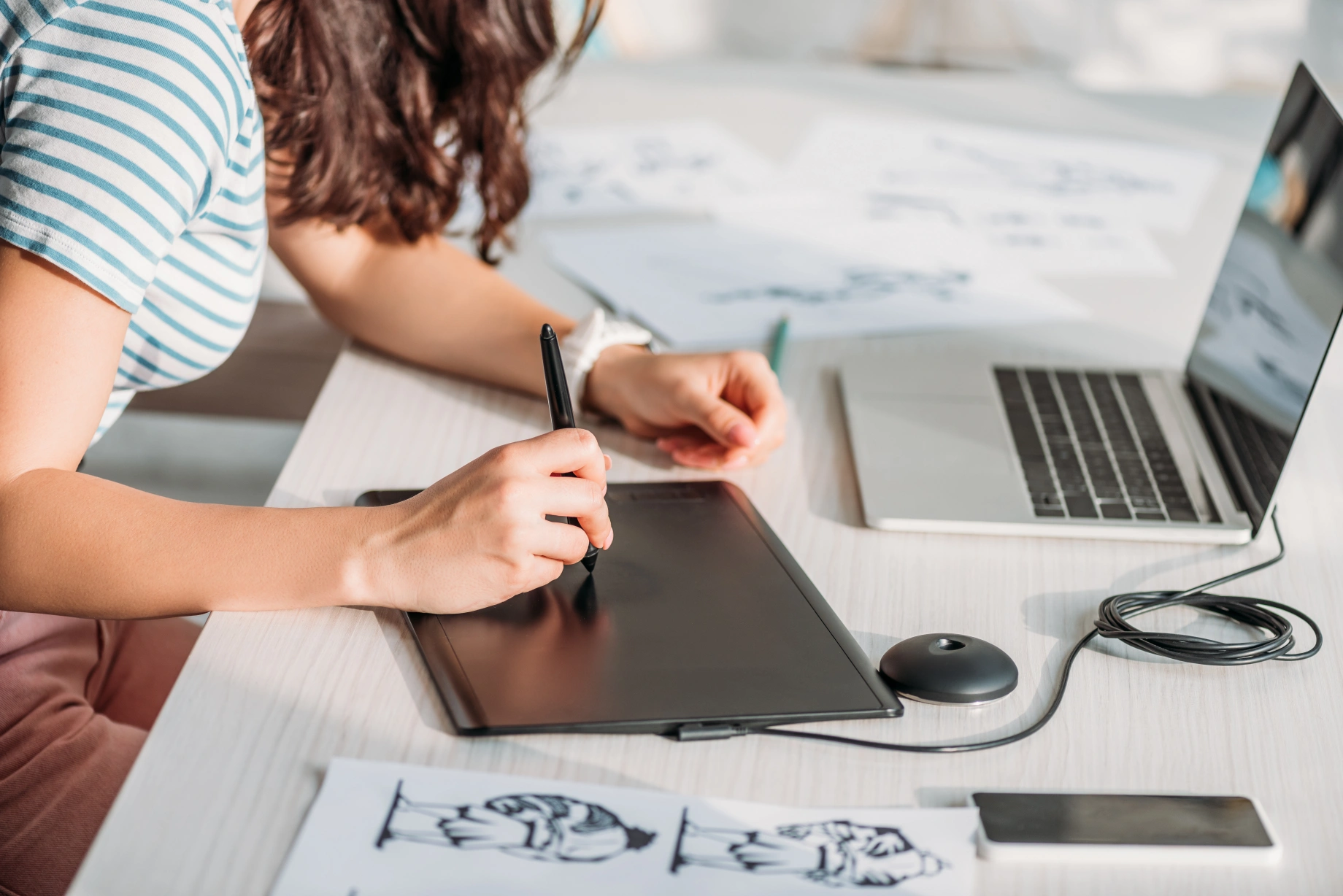 Person designing an invitation on a digital drawing tablet at a desk