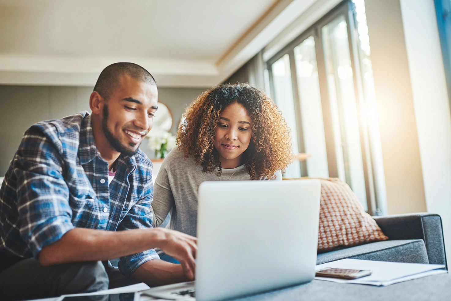 Couple viewing an invitation on a laptop in a bright living room